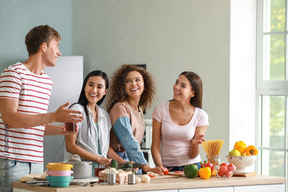 Happy friends cooking together in kitchen