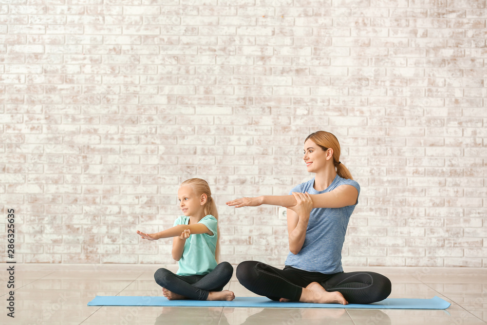 Mother with little girl doing yoga indoors