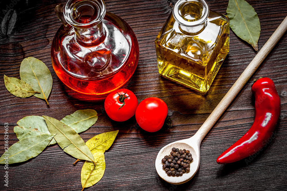 carafes with oil and tomatoes on wooden background