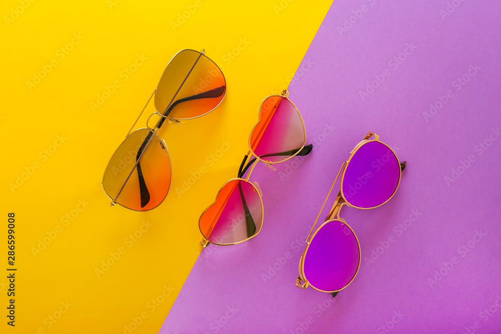 Different stylish sunglasses on color background