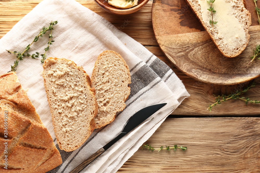 Fresh bread with butter and herbs on wooden table