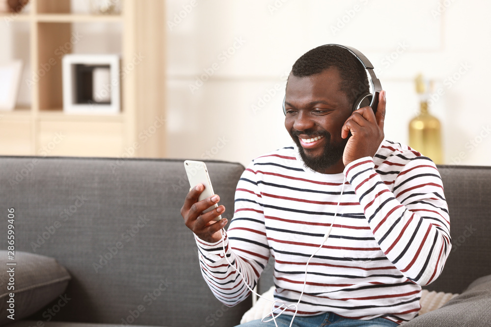 Handsome African-American man listening to music at home