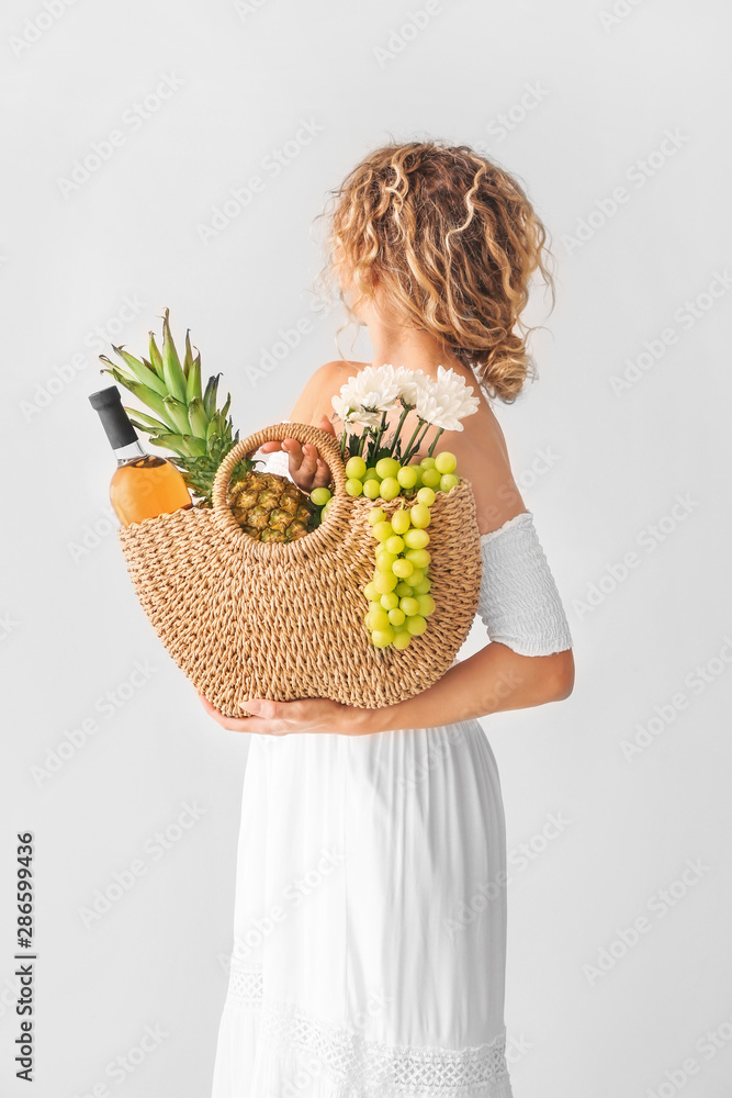 Woman with eco bag and fresh products on light background