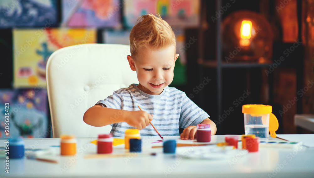 funny child boy draws laughing   with paint.