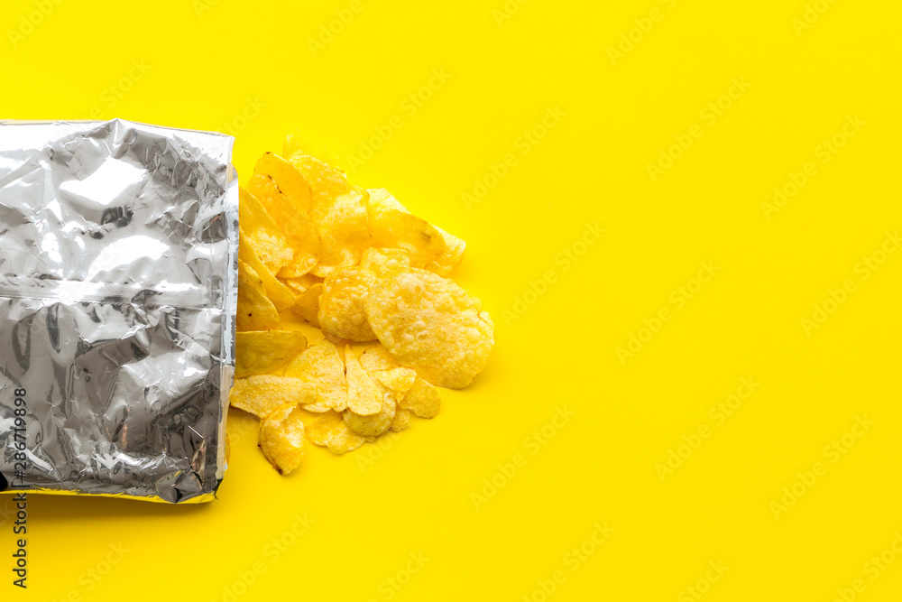 Bag of homemade potato chips for snack on yellow background top view copyspace