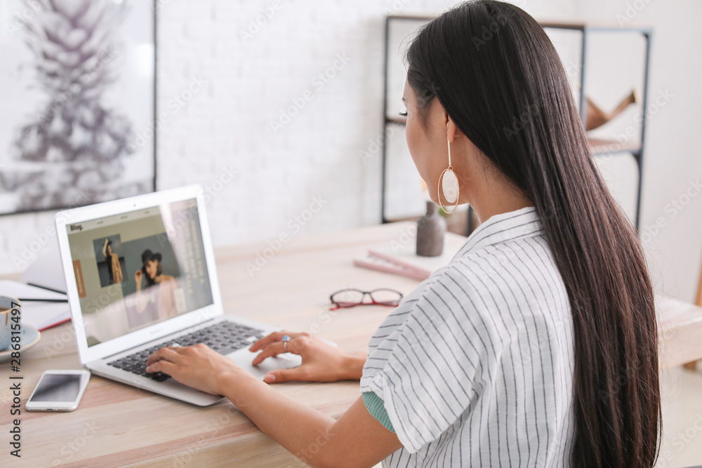 Asian beauty blogger with laptop at table