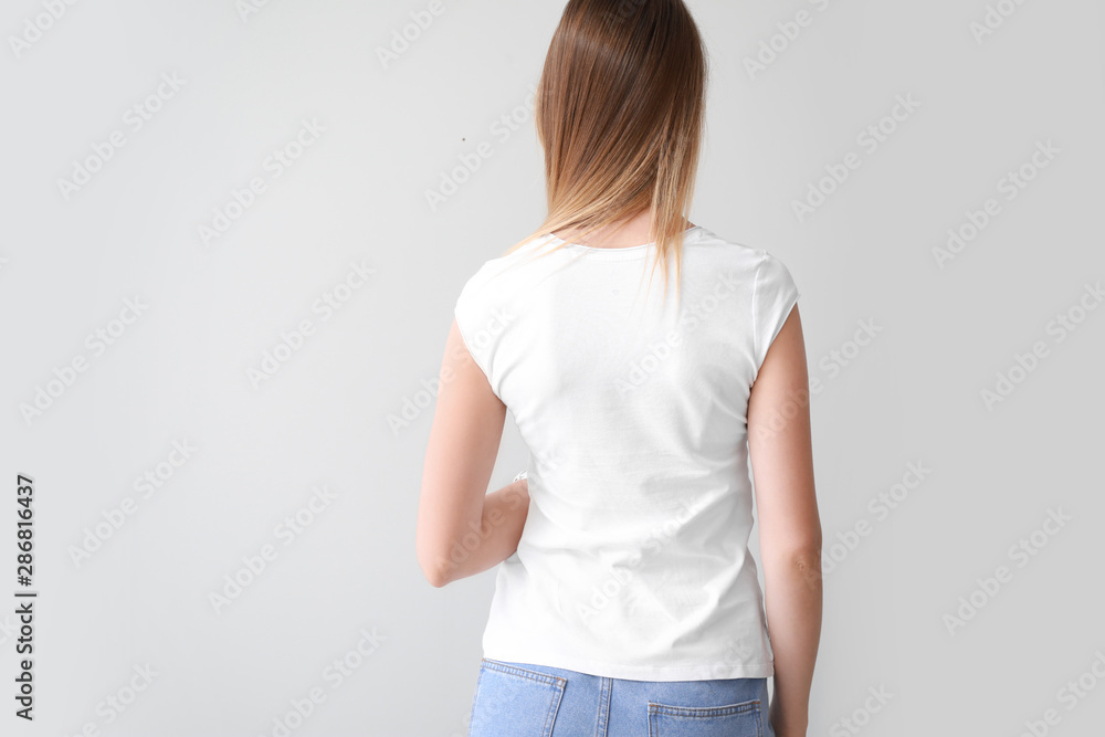 Woman in stylish t-shirt on light background, back view