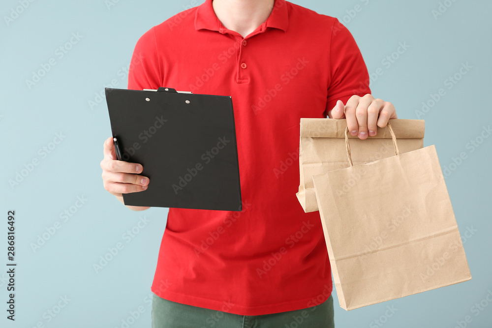 Handsome worker of food delivery service on color background