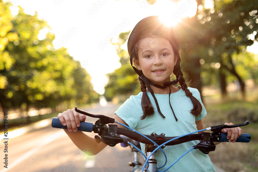 Cute girl riding bicycle outdoors