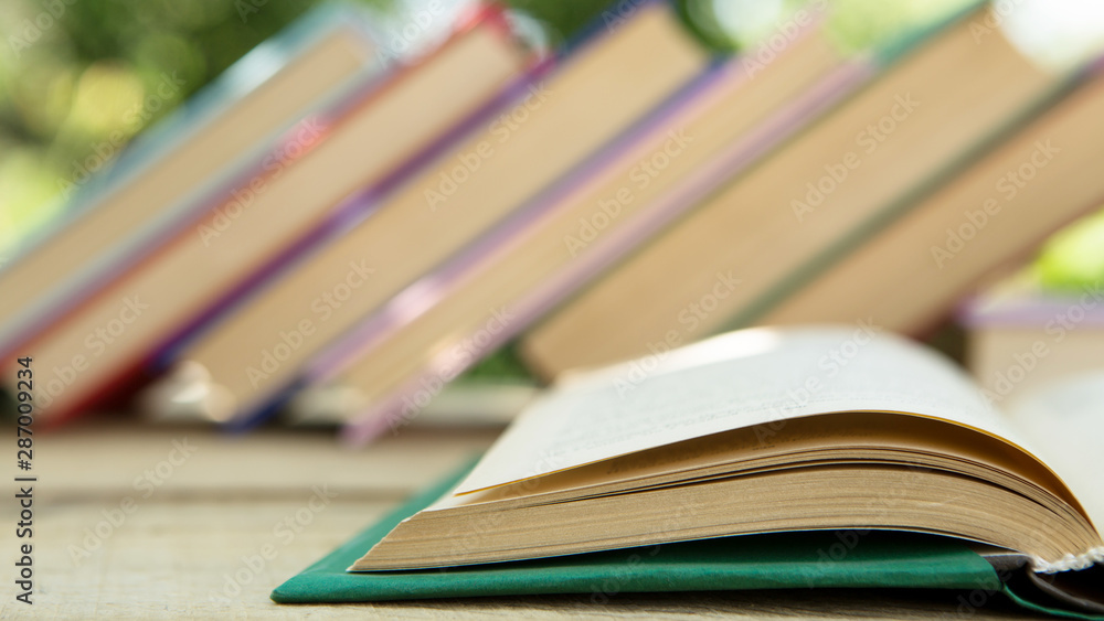 Open book on a wooden table in a garden. Sunny summer day, reading in a vacation concept