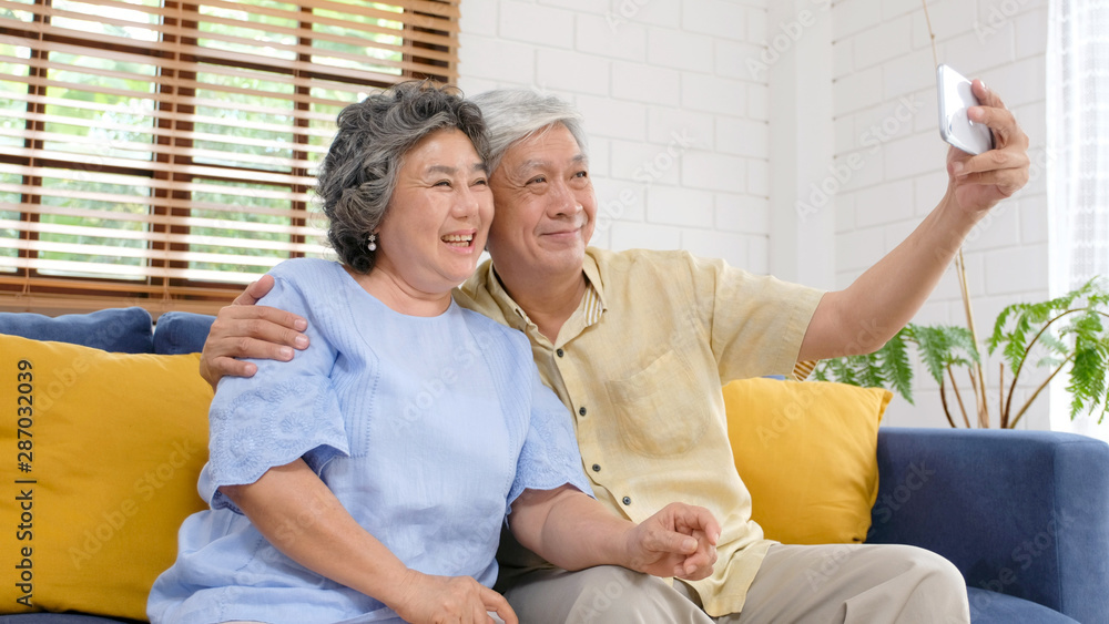 Happy senior asian couple taking selfie at home living room, active senior people in happy moment, c