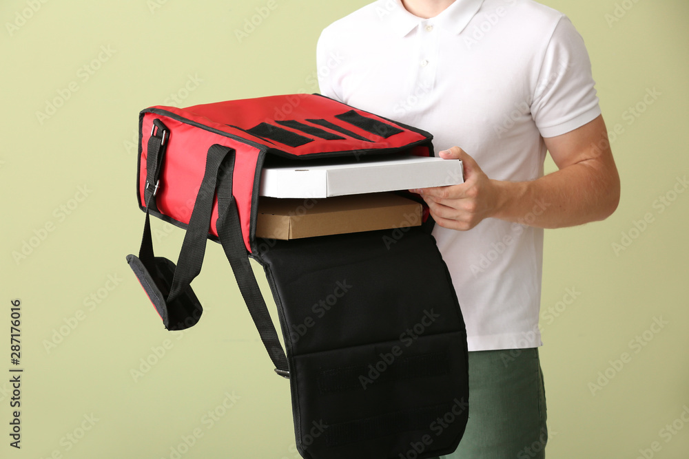 Handsome worker of food delivery service on color background