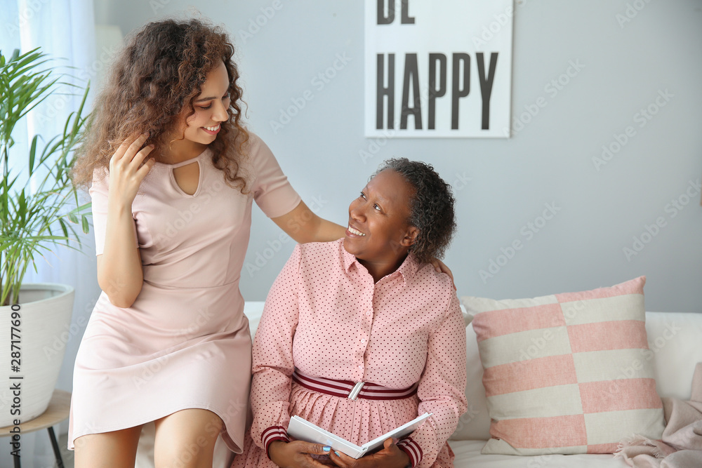 Portrait of African-American woman with her daughter reading book at home