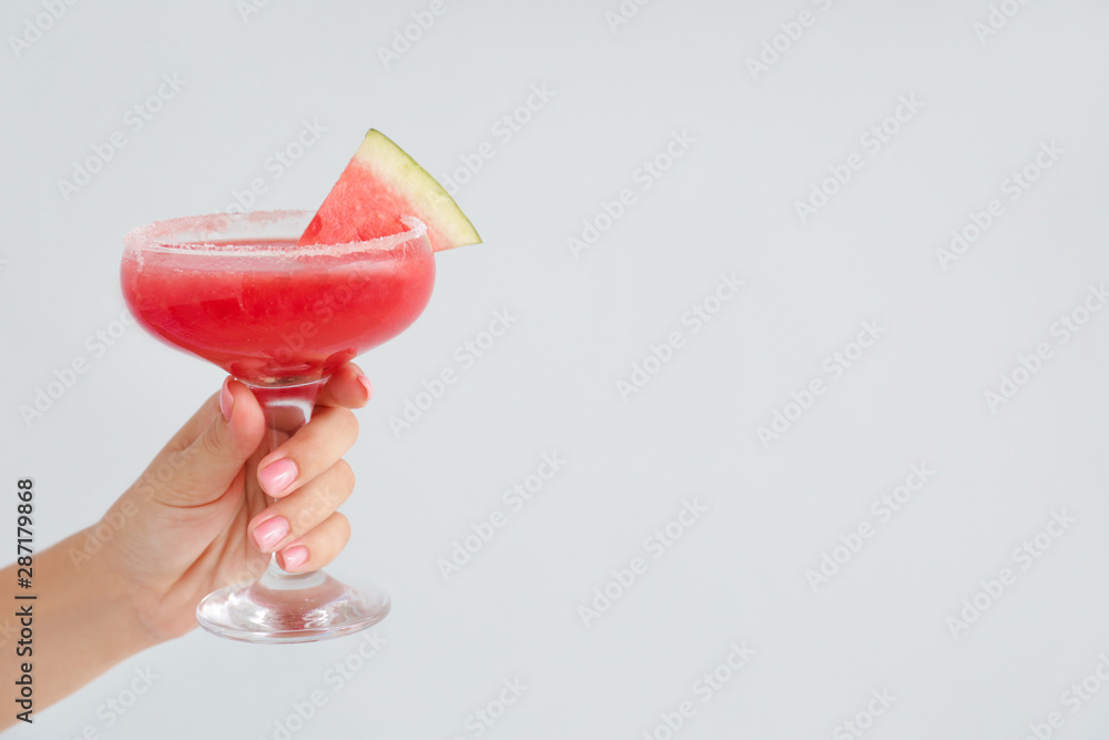 Female hand with glass of fresh watermelon juice on light background