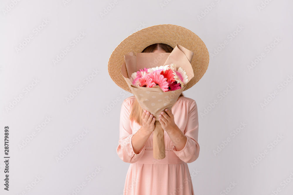 Woman with bouquet of beautiful gerbera flowers on light background