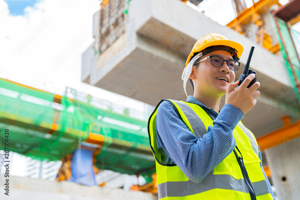 smart asian engineer manager with safety uniform checking site construction with steel and concrete 