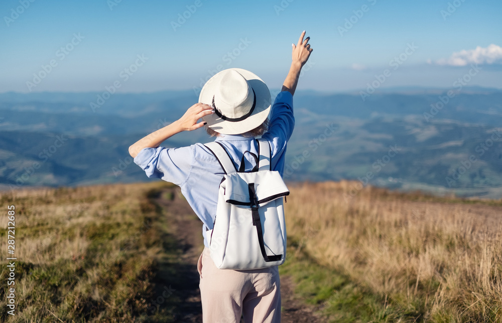 背着背包在山上徒步旅行。日落时，年轻女孩在山上行走。山