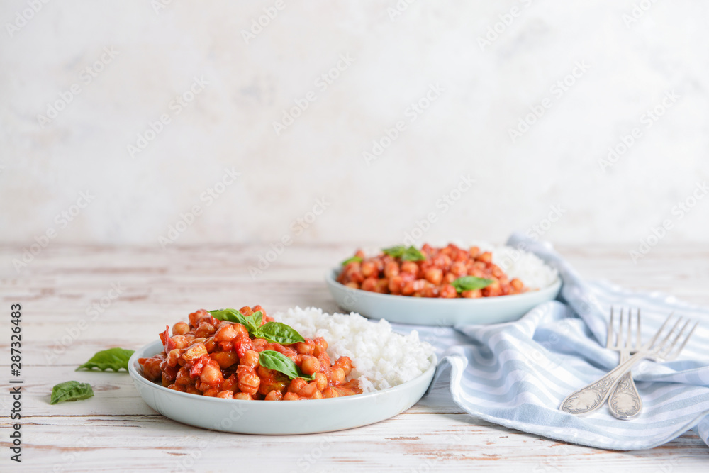 Plate with tasty chickpea in tomato sauce and boiled rice on table