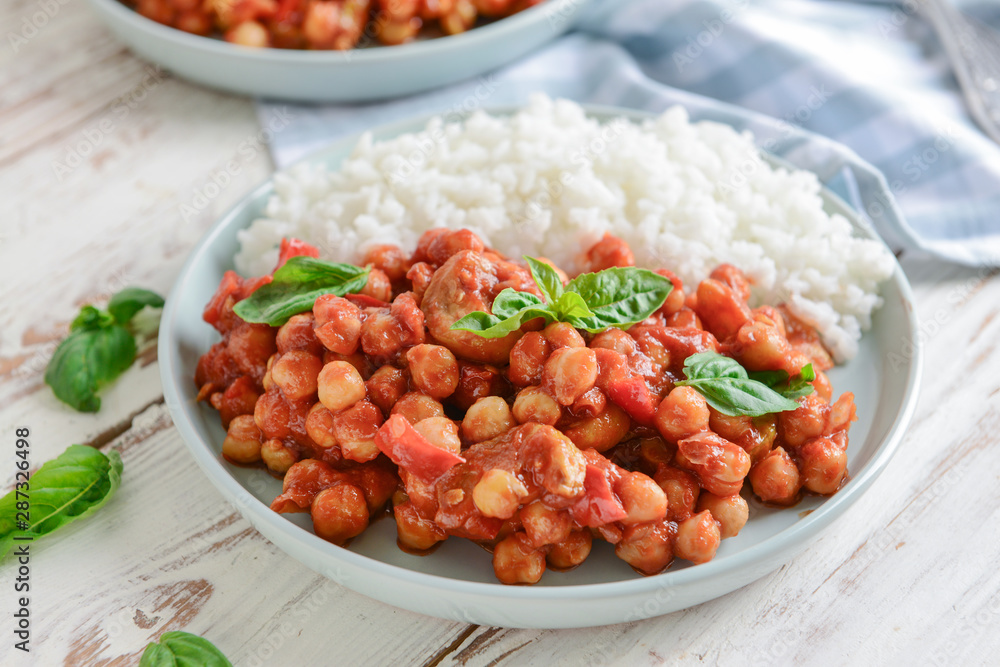 Plate with tasty chickpea in tomato sauce and boiled rice on table