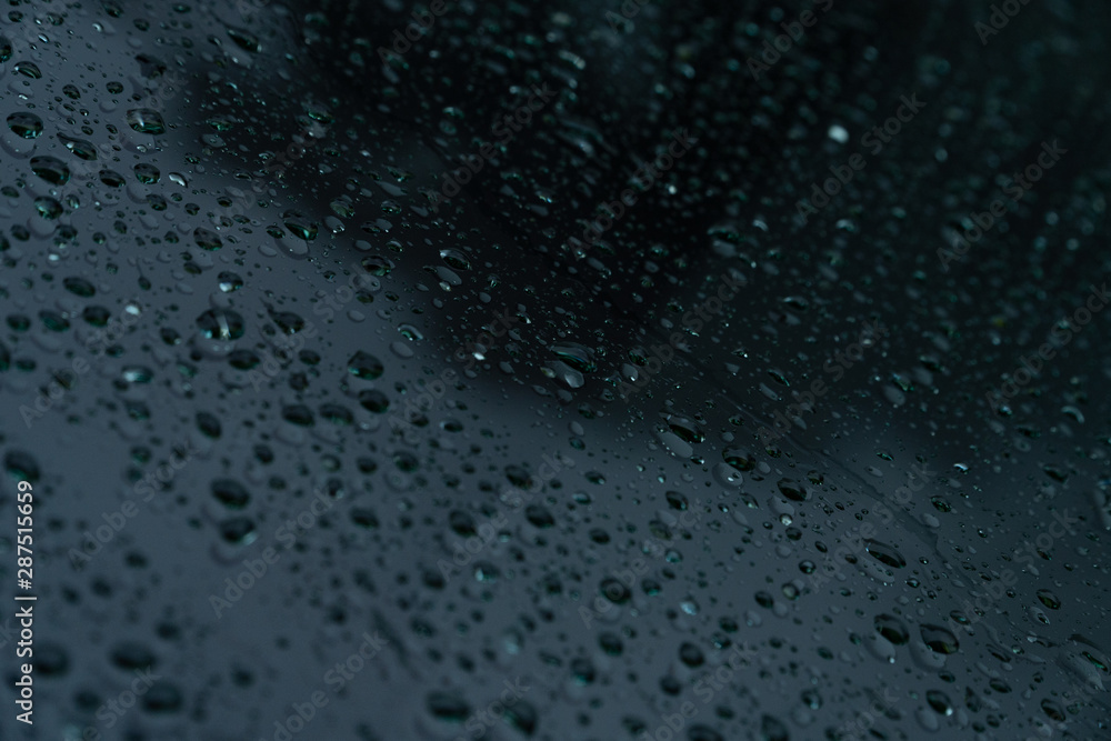 Water raindrops on a shiny dark black surface