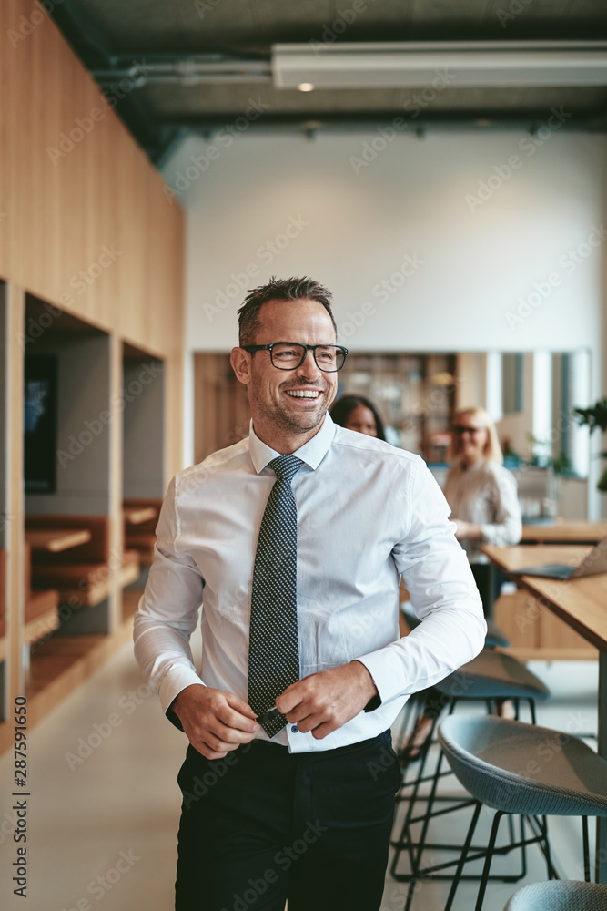 Mature businessman laughing while walking through a modern offic