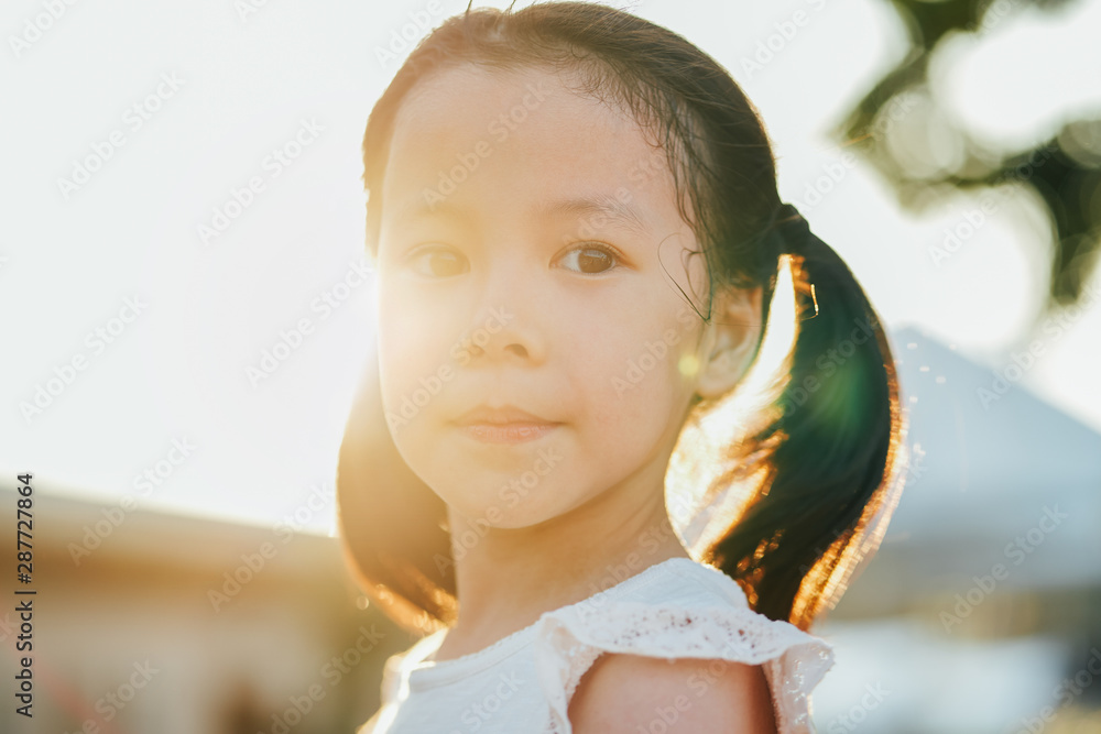 Close up portrait of little asian girl with dimples in park during sunset