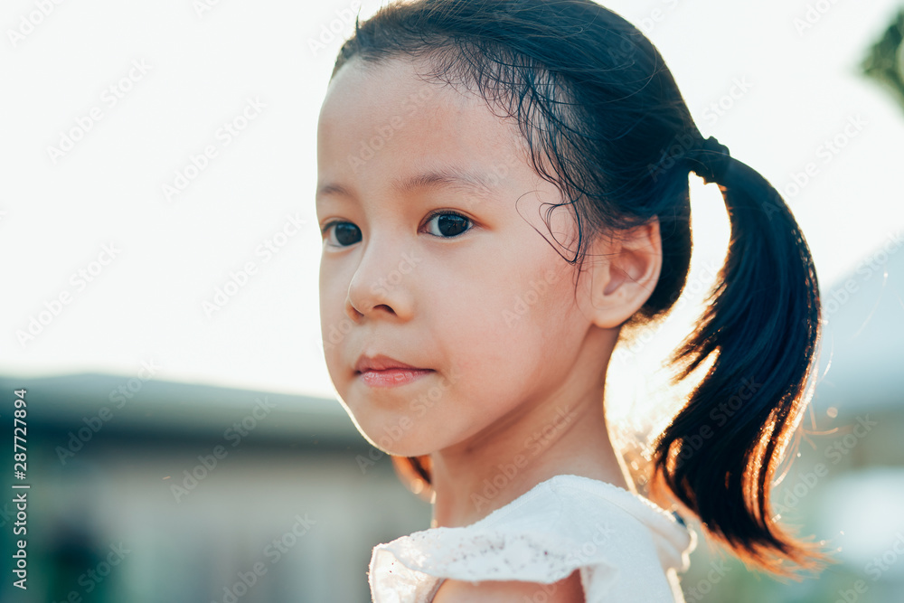 日落时分公园里有酒窝的亚洲小女孩特写