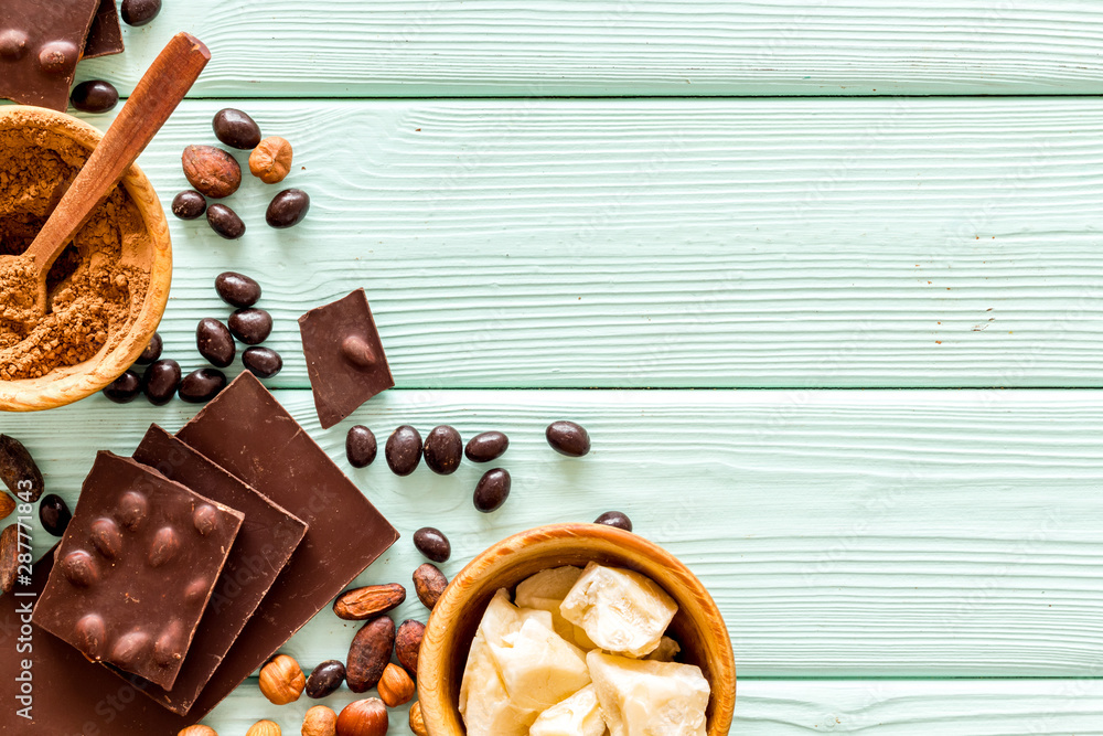 Different variety of chocolate and hazelnut on mint green wooden background top view space for text