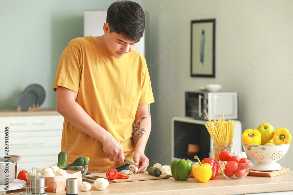 英俊的亚洲男人在厨房做饭