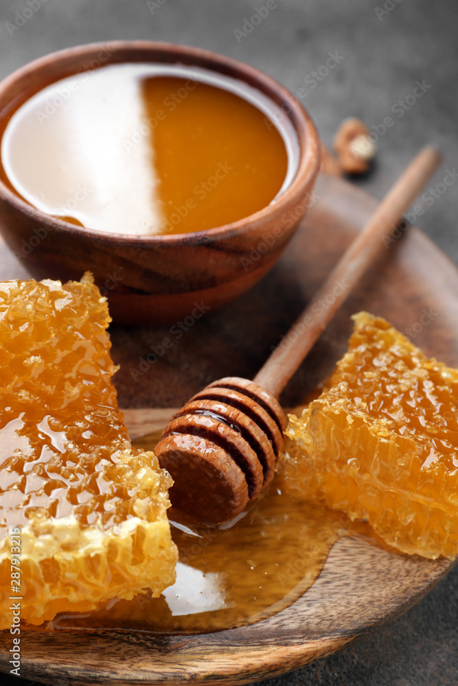 Bowl with honey, combs and dipper on table