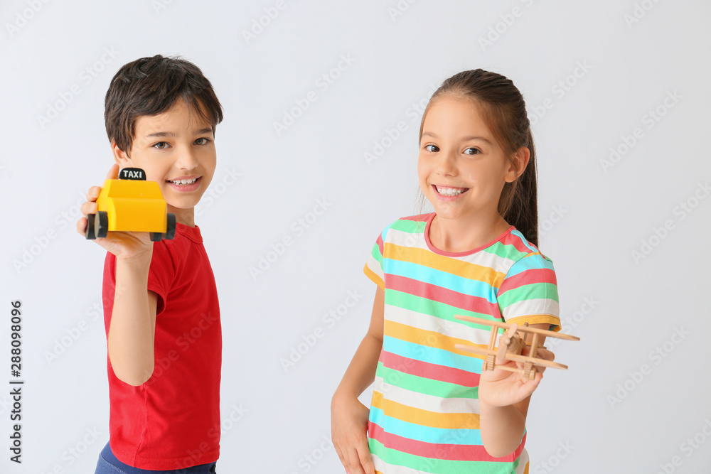 Cute little children with toys on light background