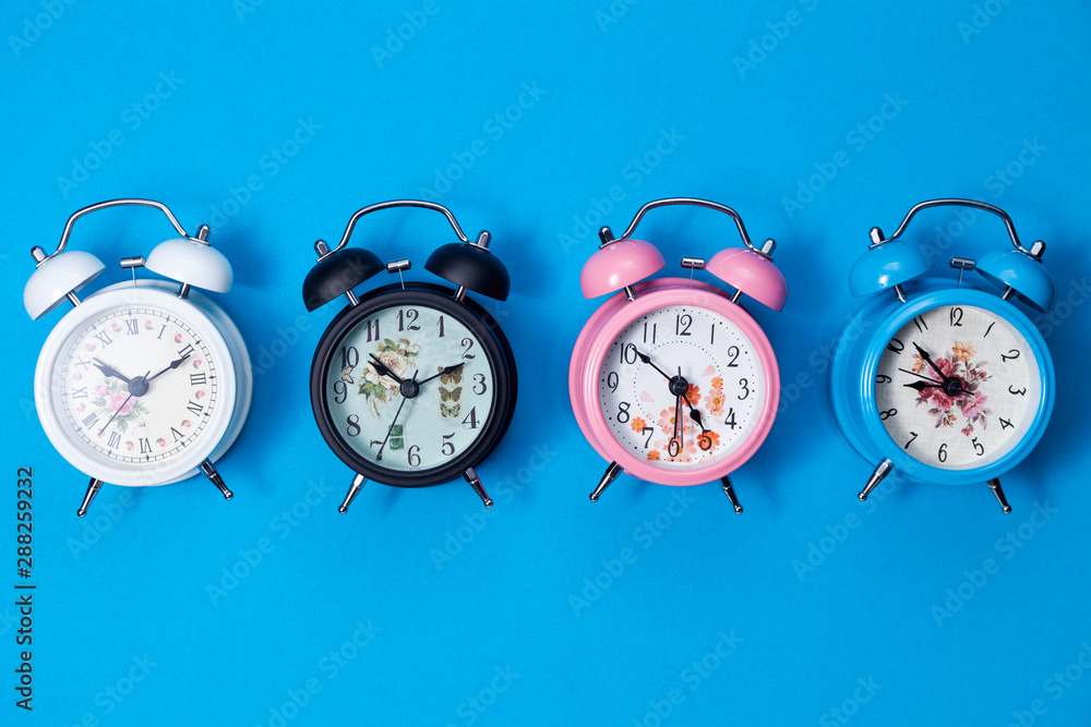 Flat lay of beautiful new alarm clock on blue paper background