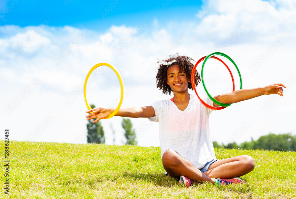 Young girl with curly hair rotate hoops in hands