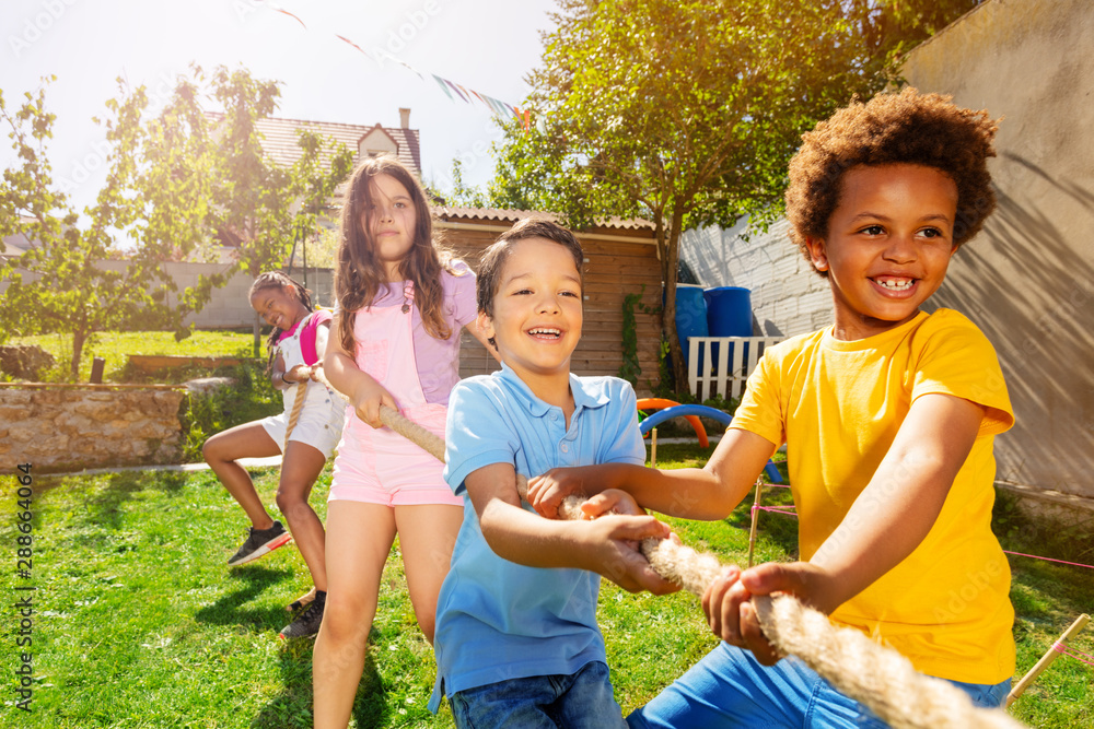 Group of kids play pulling rope game on playground