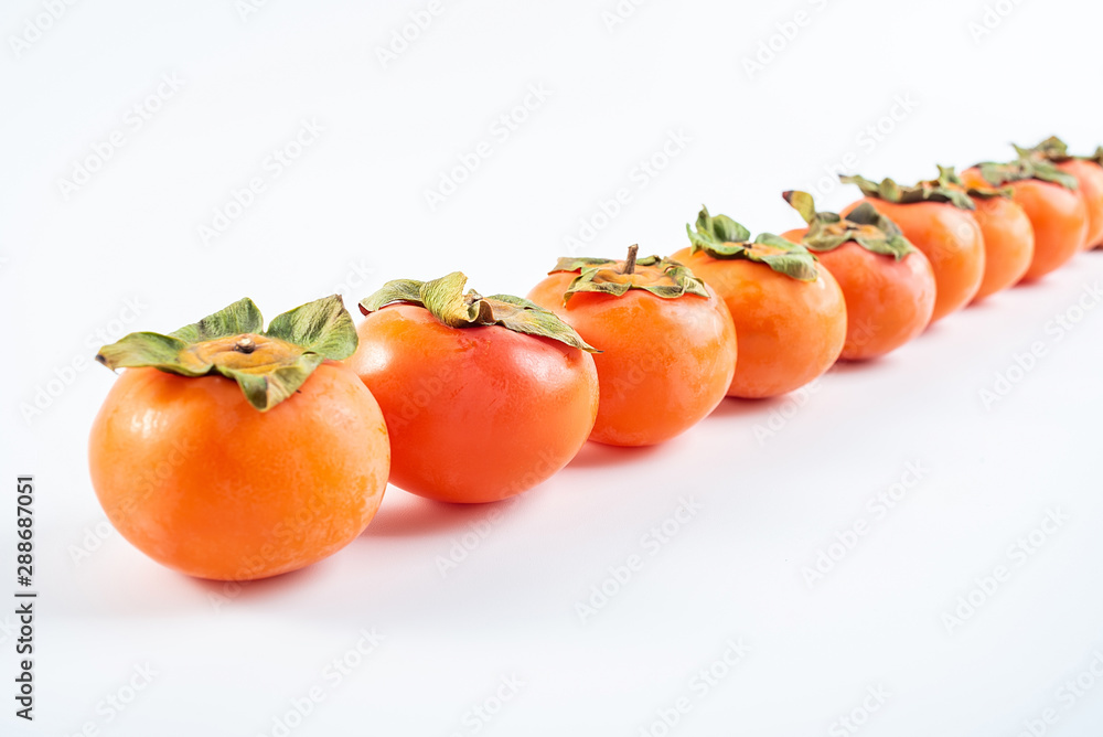 Row of red persimmons with fresh fruits on white background