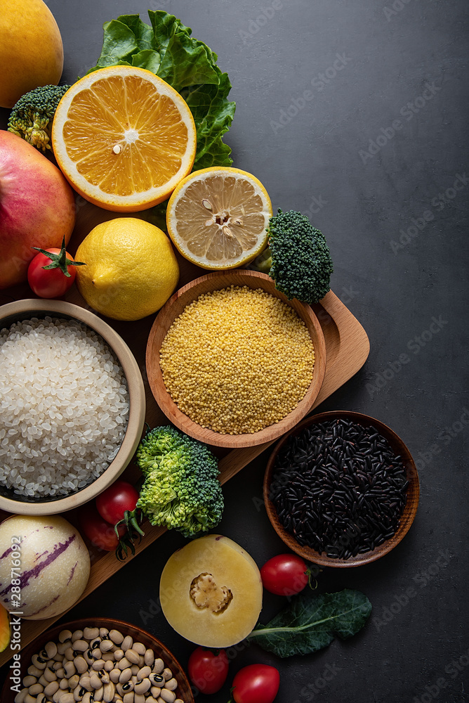 Bunch of fresh seasonal fruits, vegetables and grains of legumes on a black background