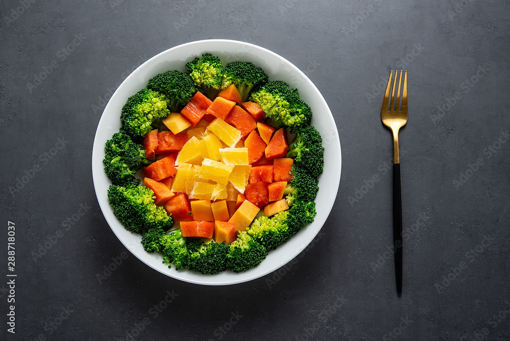 A plate of nutritious delicious fruit and vegetable salad on a black background