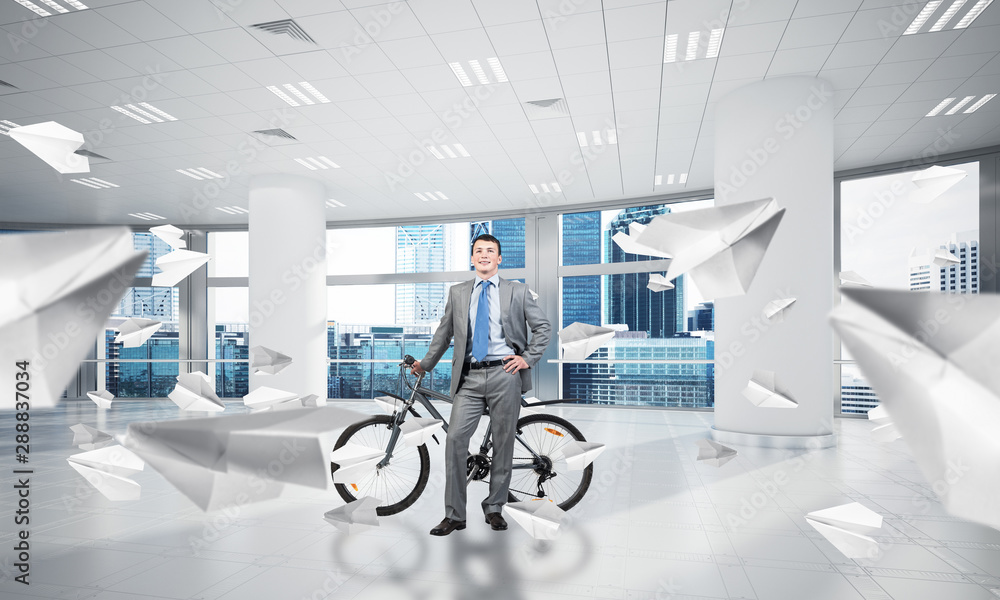 Smiling man in business suit standing with bike