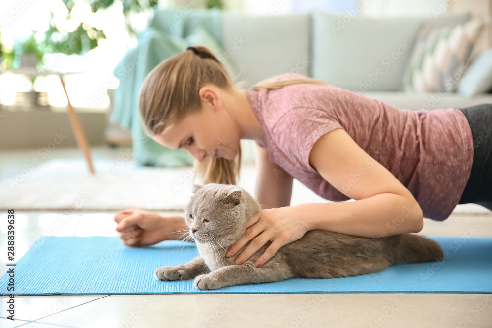 美丽的女人和可爱的猫在家做瑜伽