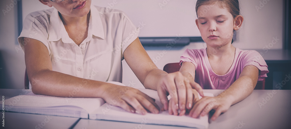 Teacher assisting blind student in library