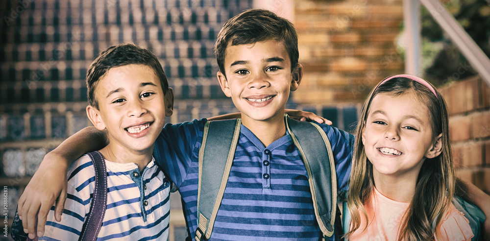 Smiling school kids standing with arm around