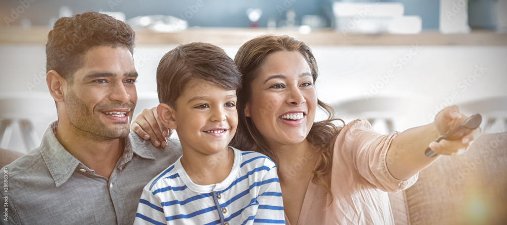 Parents and son watching television in living room