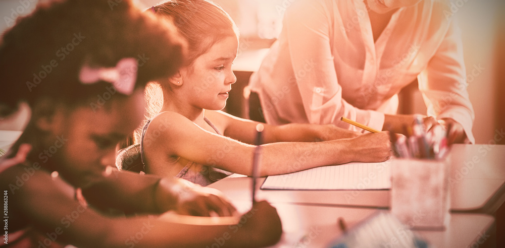 Teacher helping kids with their homework in classroom