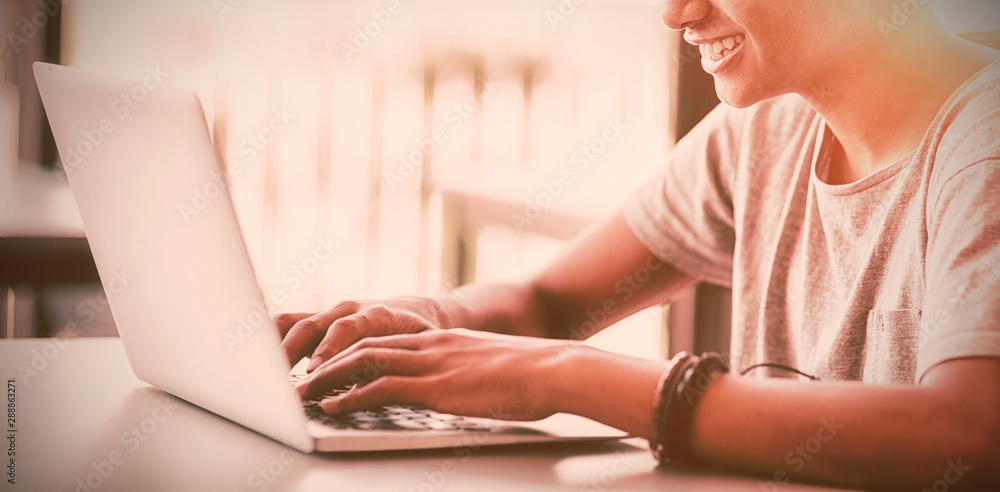 Happy schoolboy using laptop in classroom