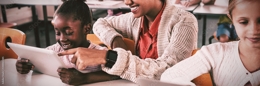 Teacher helping student with tablet computer