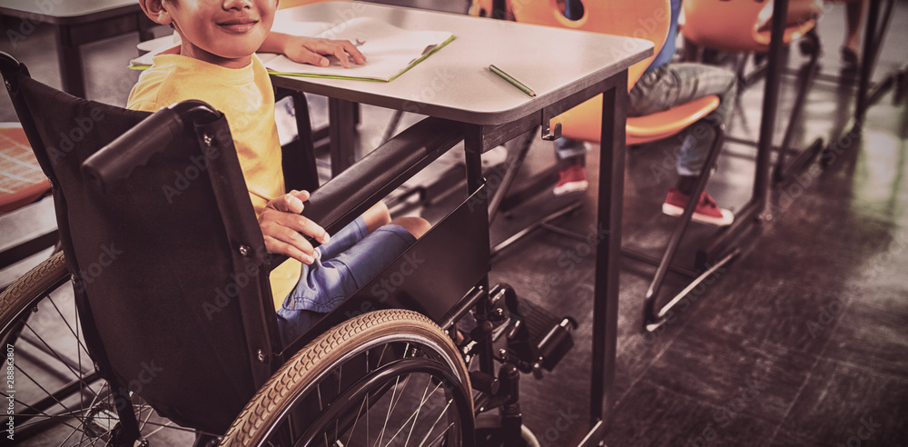 Cute boy on wheel chair sitting in class