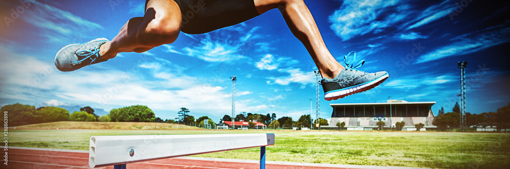 Female athlete jumping above the hurdle