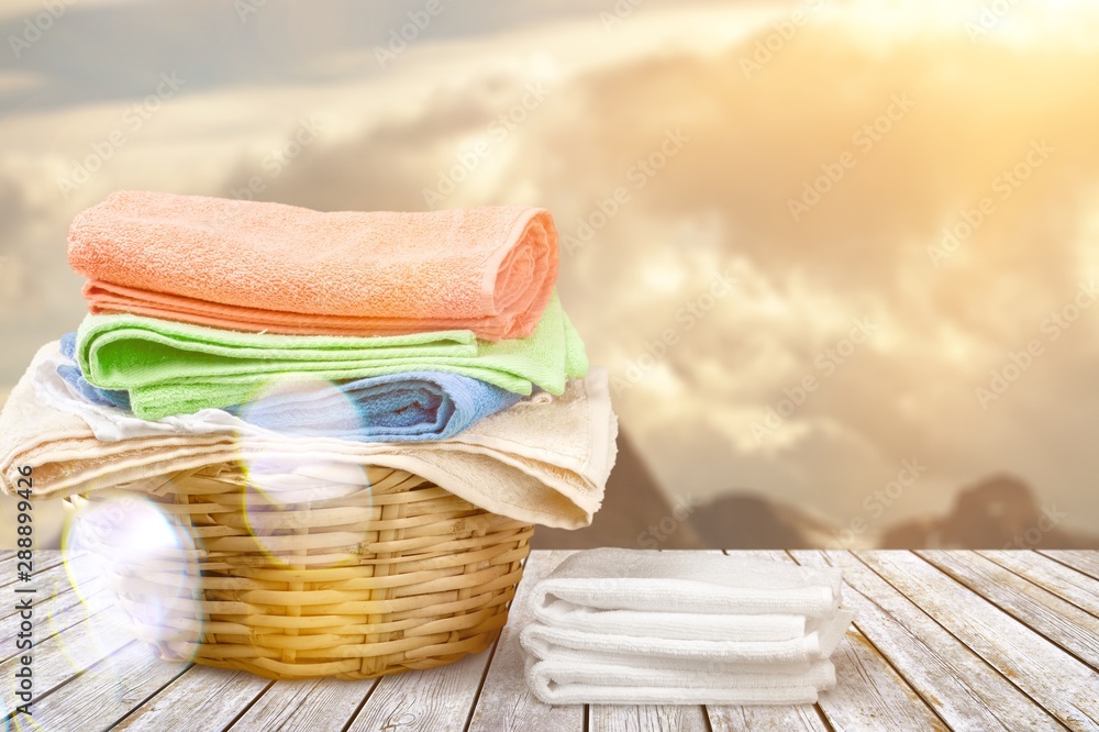 Laundry Basket with colorful towels on wooden table