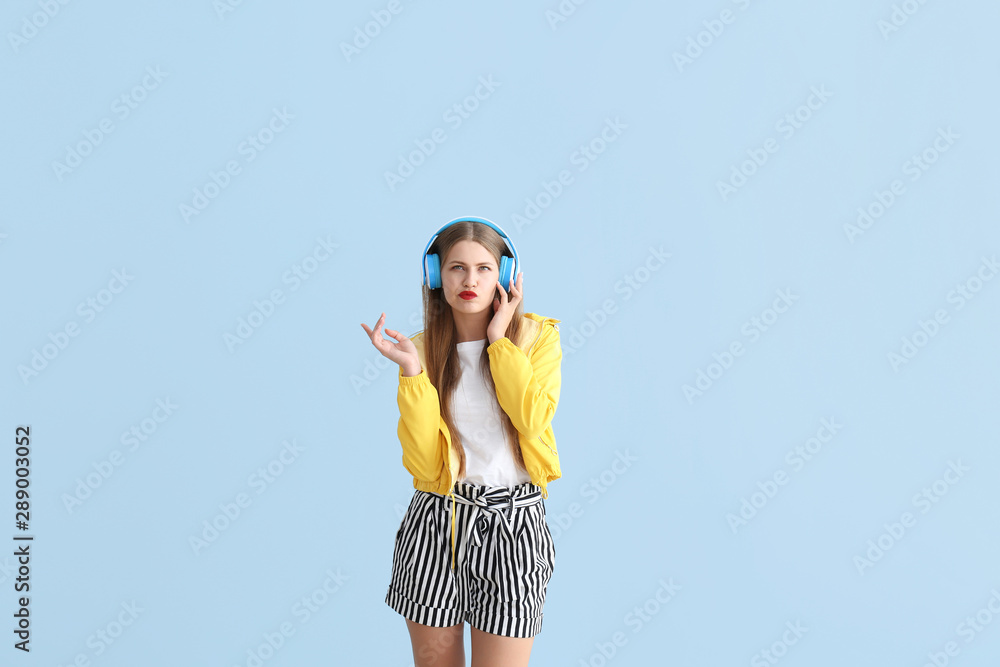 Thoughtful young woman listening to music on color background