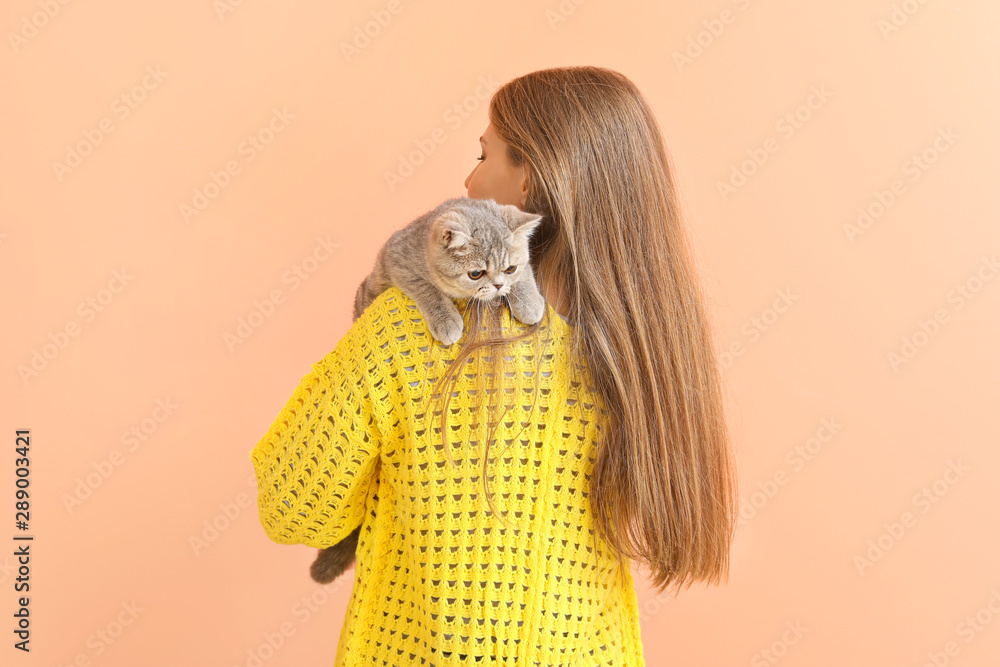 Beautiful young woman with cute cat on color background